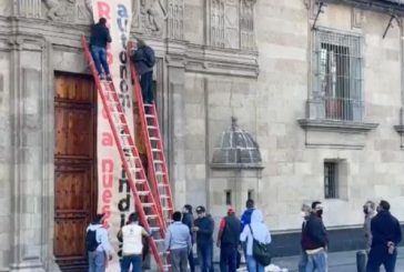 Electricistas tiran la valla de Palacio Nacional y cuelgan una pancarta